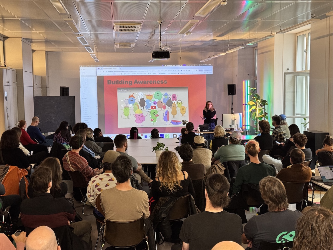 Susanna is giving a talk in front of a large audience in the EGC studio. She's currently showing 'Dumb ways to die' to show that serious issues can be presented in a playful way.