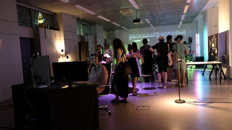 Image of the EGC studio during the Angewandte Festival. There are a couple of people, in the very back you can see a projection of the current event 